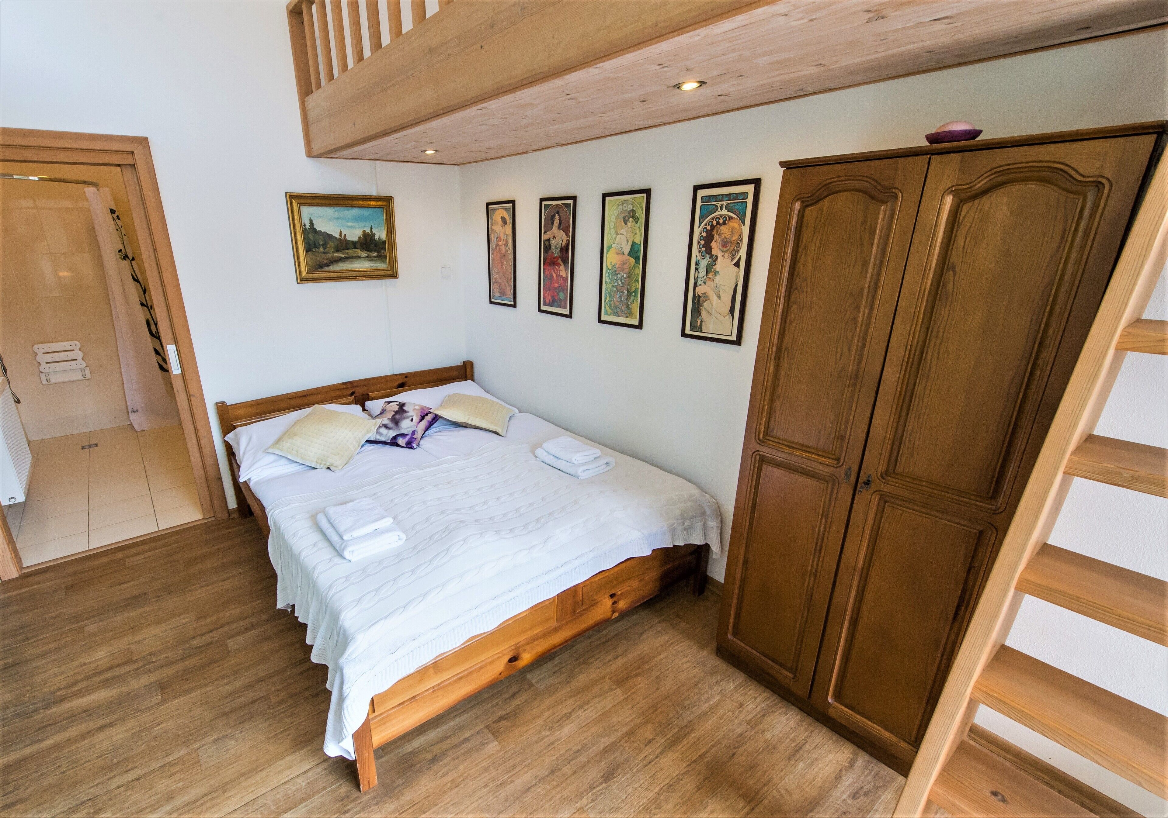 A bedroom with a wooden bed, a wardrobe, and a painting on the wall.