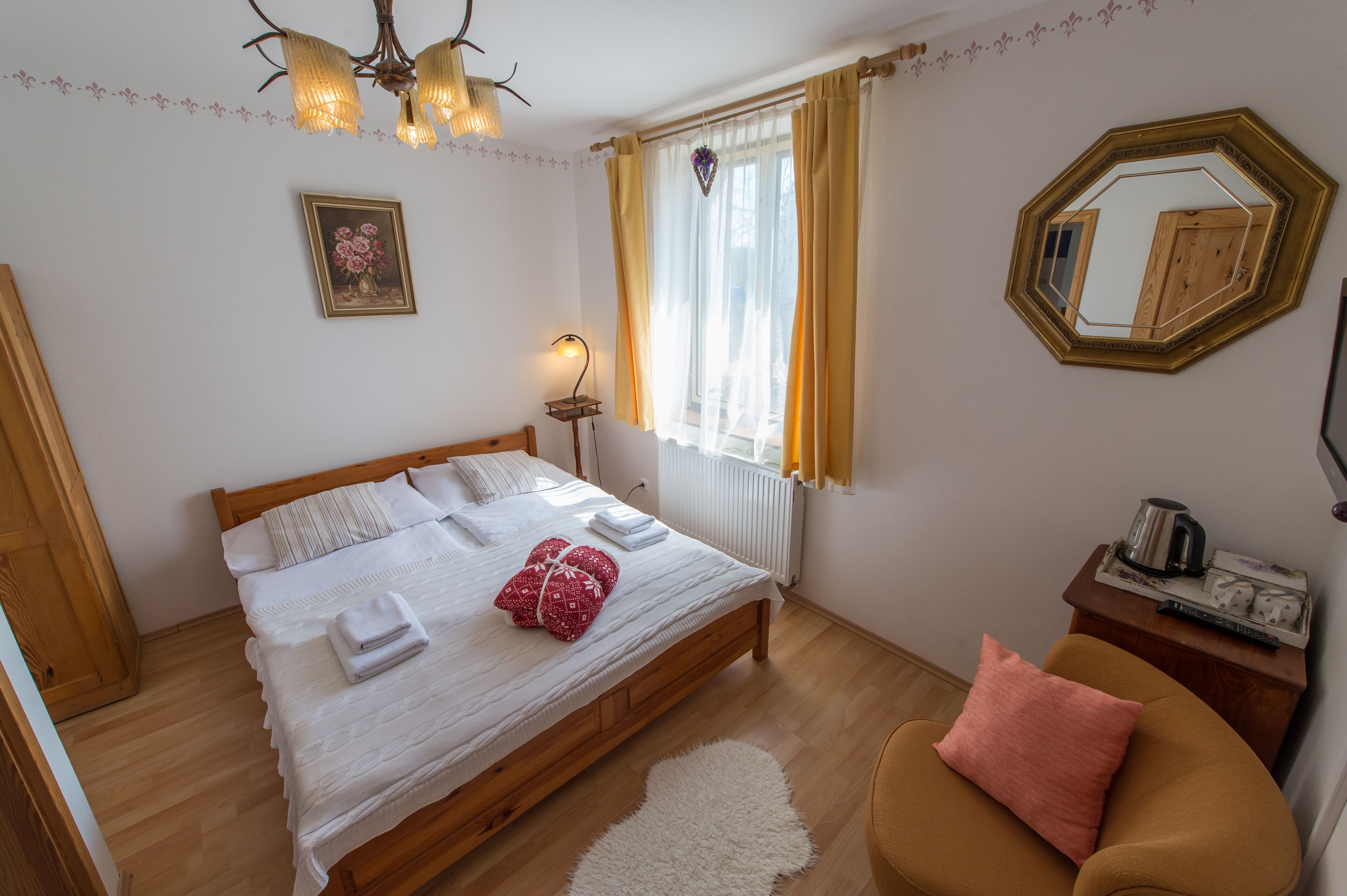 A neatly made bed with white linens, a wooden headboard, and a bedside lamp.