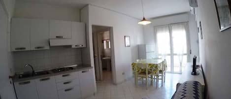 A compact living space with a kitchenette, dining area, and a sofa.