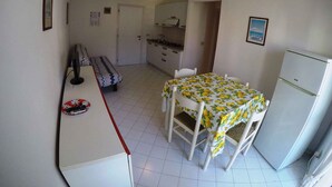 Eine kompakte Küche mit Esstisch, Stühlen, einem Kühlschrank und einer Bank.