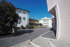 A parking lot with a building on the left and a building on the right. - Holiday apartment near the beach (Rosolina Mare)
