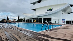 A swimming pool on a deck with a modern building in the background. - The Streamliner Hotel Apartment (Toamasina)