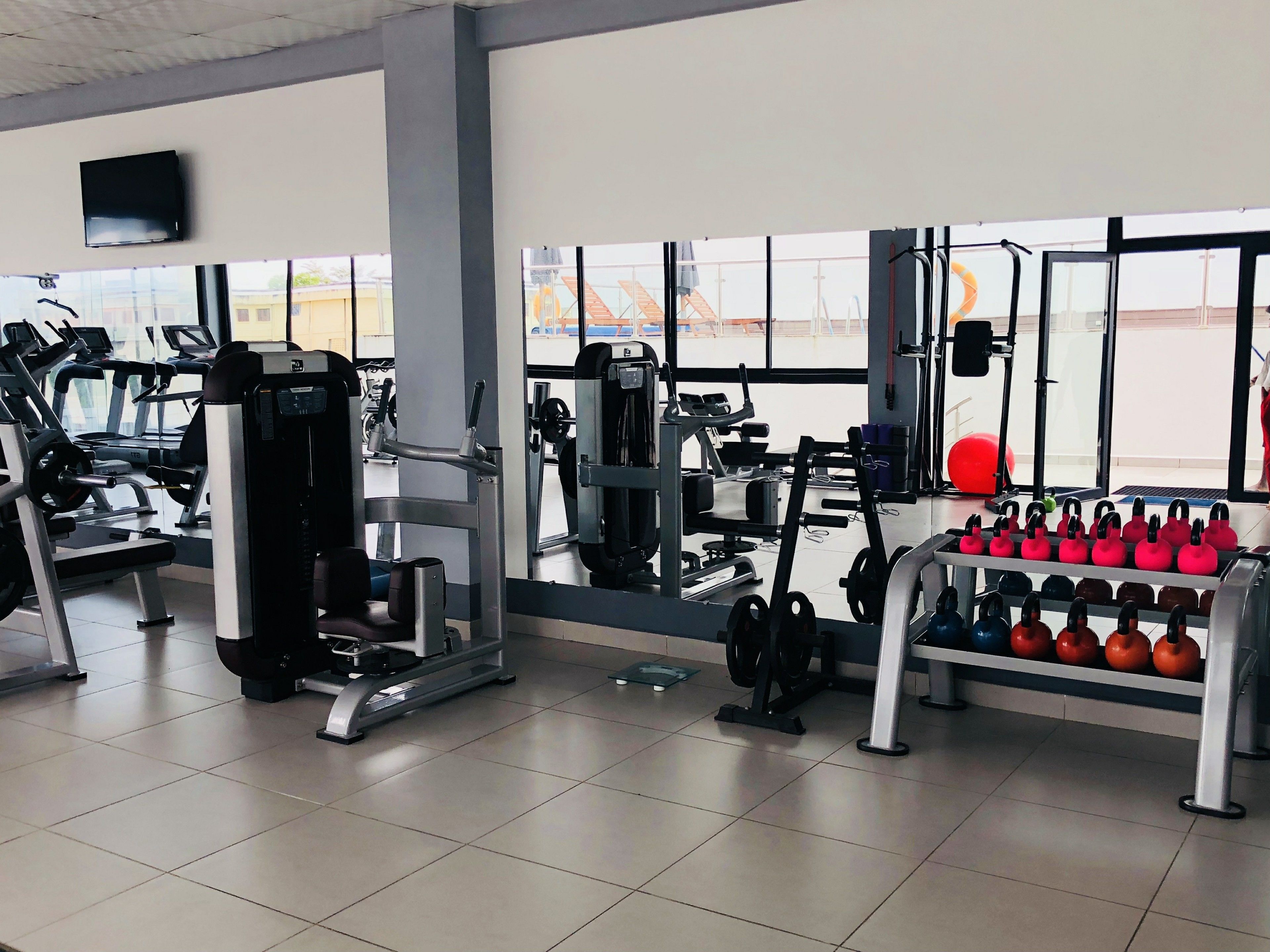 A gym with exercise equipment, a treadmill, and kettlebells.
