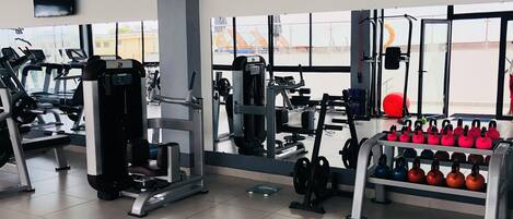 A gym with exercise equipment, a treadmill, and kettlebells.