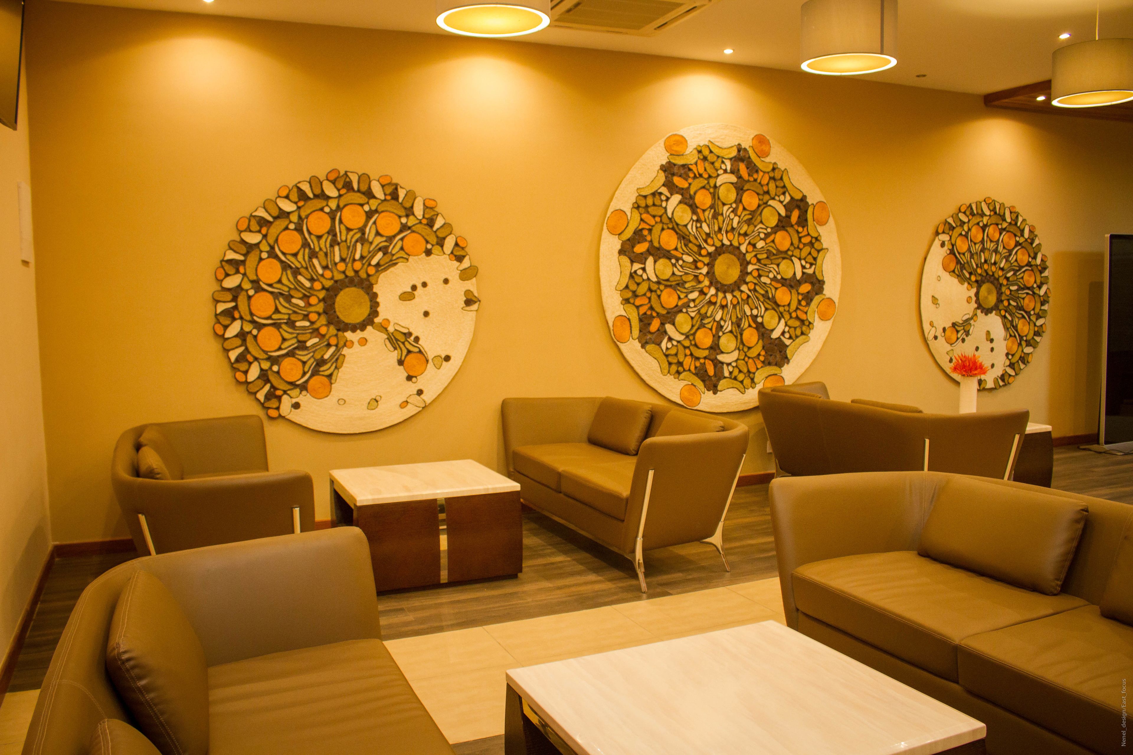 A modern lounge area with sofas and a coffee table, featuring three large circular wall art pieces.
