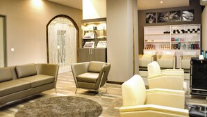 A modern hotel lobby with a sofa, armchairs, a reception desk, and a display of toiletries. - The Streamliner Hotel Apartment (Toamasina)