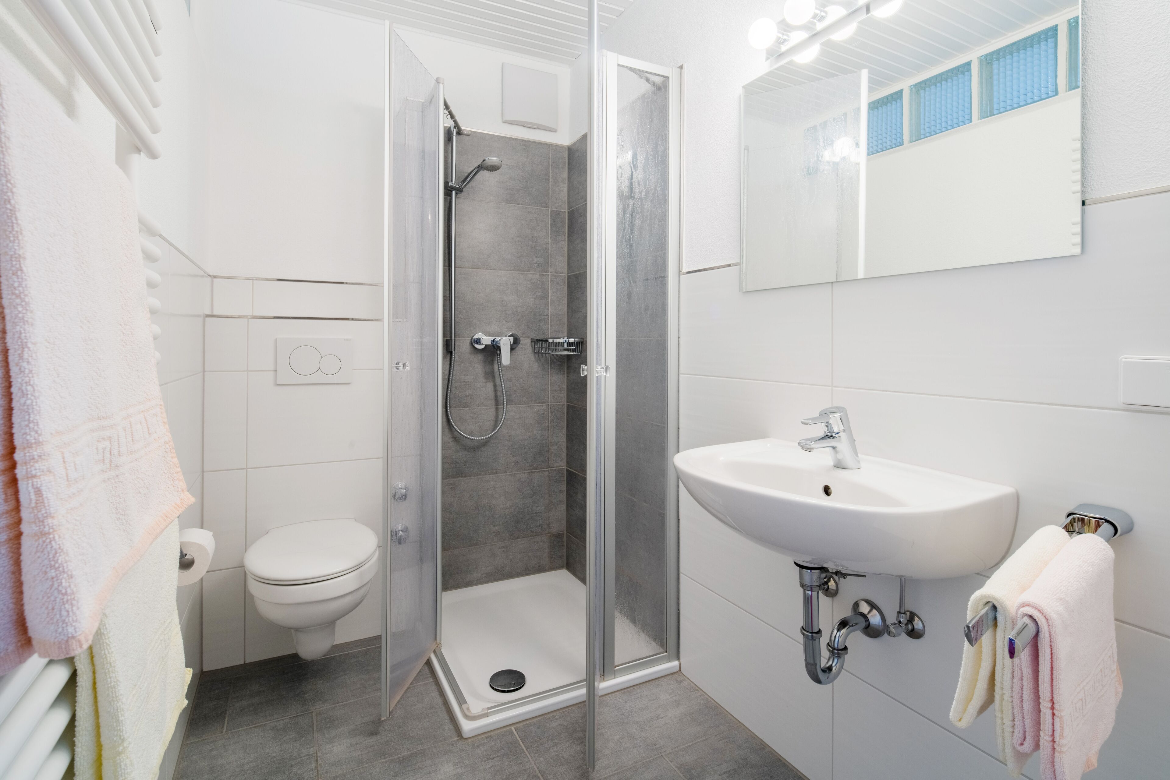 A modern bathroom with a shower, toilet, and sink.