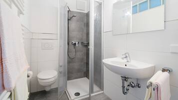 A modern bathroom with a shower, toilet, and sink.