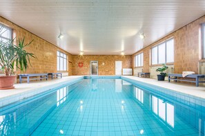 An indoor swimming pool with tiled walls and benches along the sides. - Haus Anny (Deudesfeld)