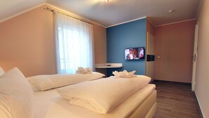Una habitación de hotel con dos camas, un televisor en la pared y la puerta del baño.