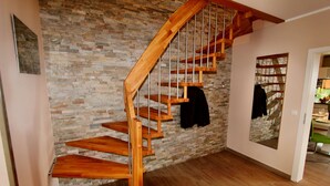 Una escalera de madera con un muro de piedra de fondo.
