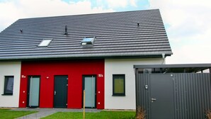 Una casa moderna con fachada roja, techo gris y portón gris.