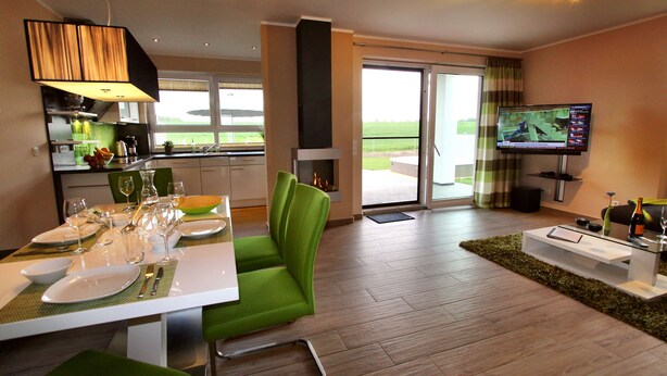 Una sala de estar moderna con comedor, televisión de pantalla plana y vistas al exterior.