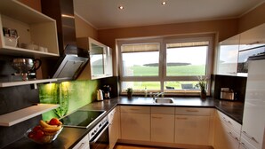 Una cocina moderna con armarios blancos, encimera negra y ventana con vistas al campo.
