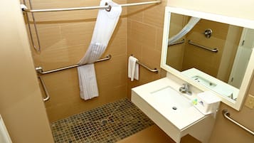 A bathroom with a shower, grab bars, a sink, and a mirror.