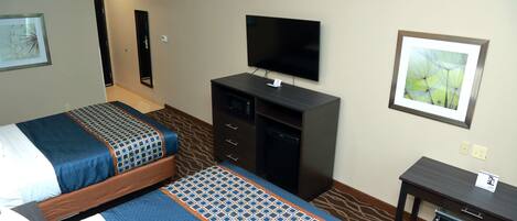A hotel room with two beds, a TV, a desk, and a chair.