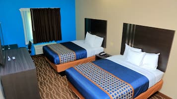 Habitación de hotel con dos camas, cada una con cabecero, un escritorio y una silla.