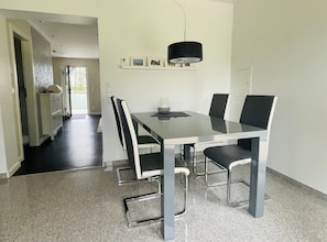 A modern dining area with a rectangular table, four chairs, and a pendant light.