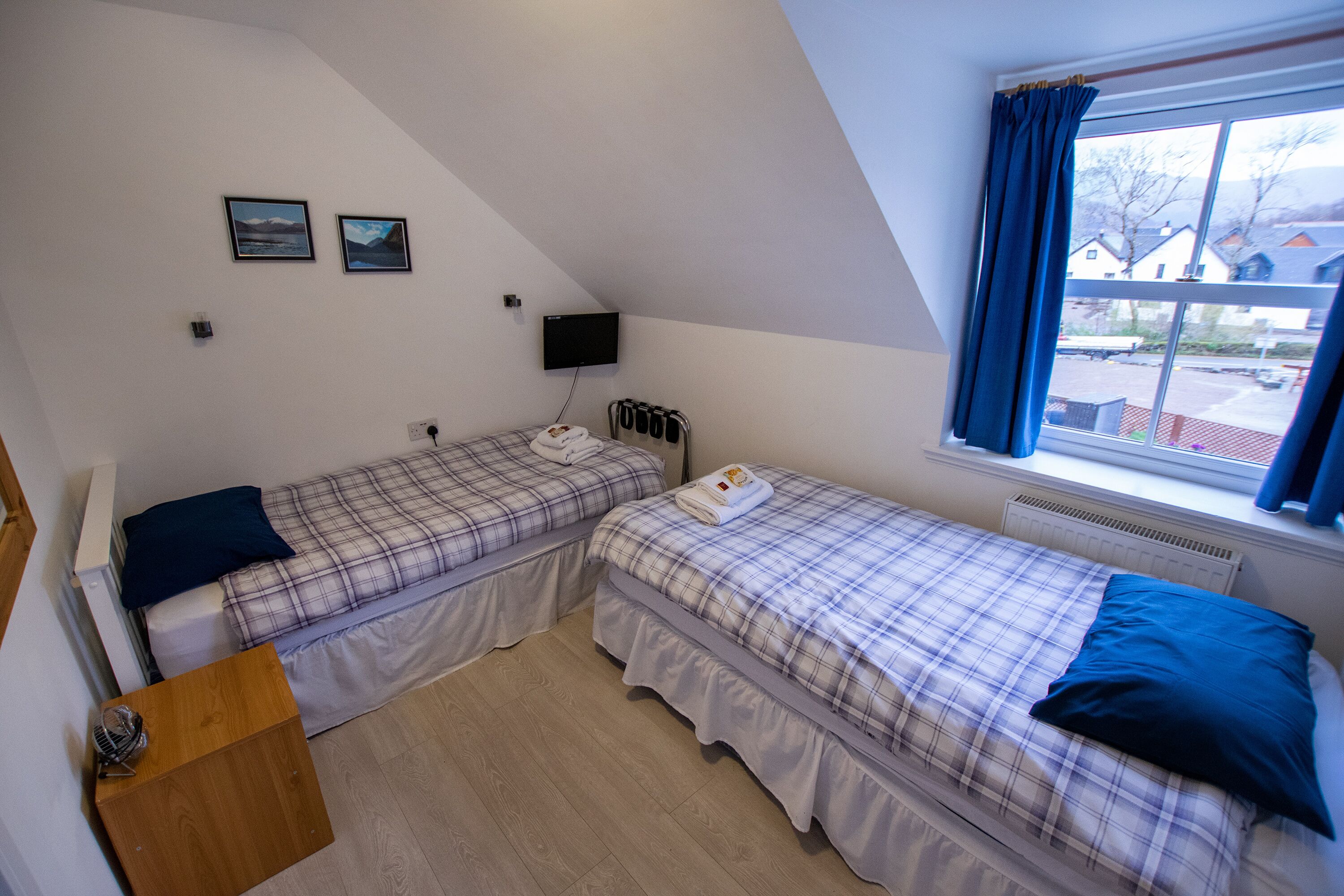 Une chambre avec deux lits, une télévision et une fenêtre avec des rideaux.