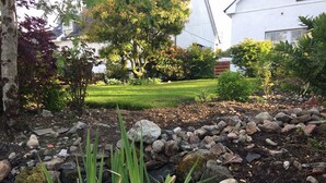 Un jardin où l’on trouve une grande variété de plantes et un petit élément décoratif aquatique.
