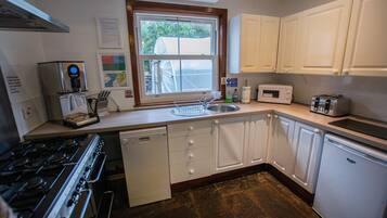 A compact kitchen with white cabinets, a dishwasher, a stove, a microwave, and a toaster.