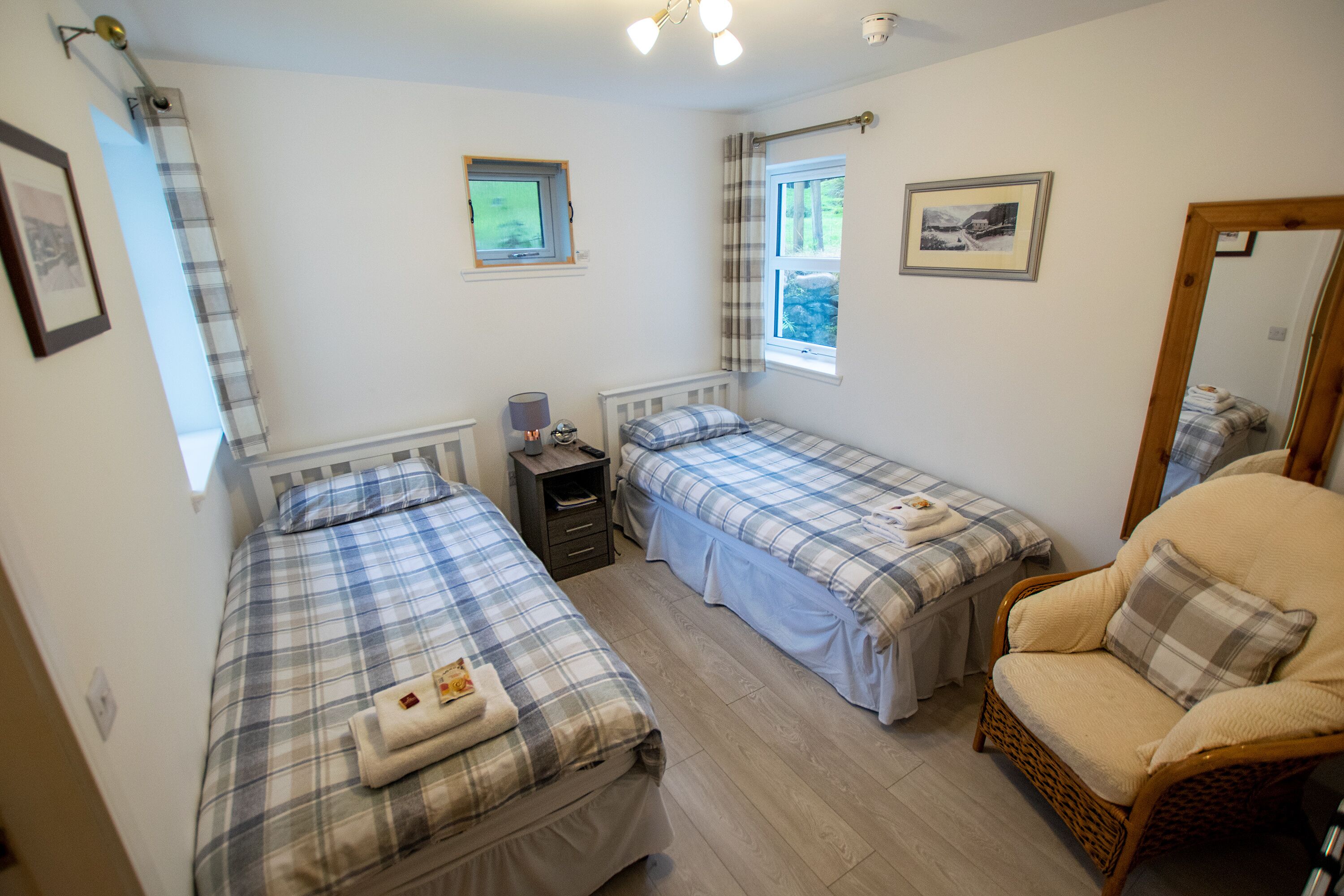 A bedroom with two beds, a chair, a nightstand, and a window.
