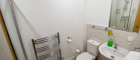 Ein modernes Badezimmer mit Duschkabine aus Glas, Toilette und Waschbecken mit Handtuchhalter.