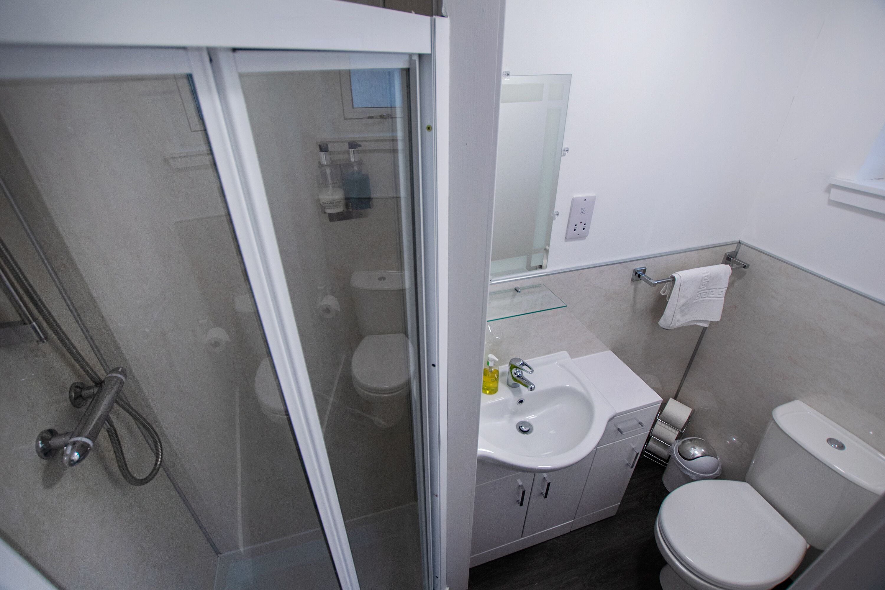 Une salle de bain moderne avec une douche à parois de verre, un lavabo blanc et des toilettes.