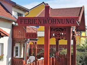 Une pancarte en bois indiquant « FERIENWOHNUNG » et « FREI », ce qui signifie qu’il s’agit d’une maison de vacances ou d’une chambre d’hôtes disponible.