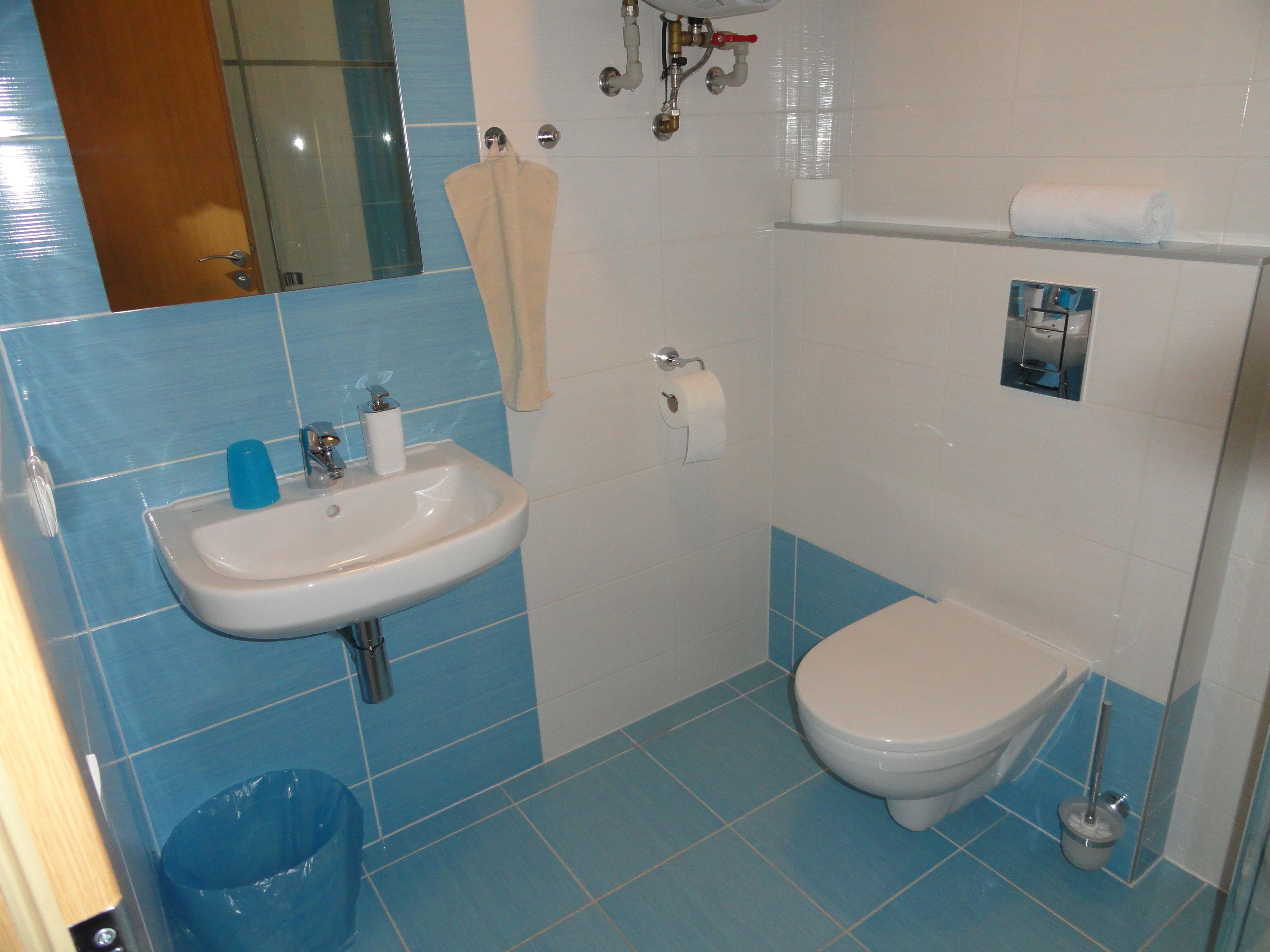 A bathroom with a sink, toilet, and blue-tiled walls.