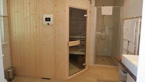 Een sauna met een houten buitenkant, een glazen deur en een bedieningspaneel.