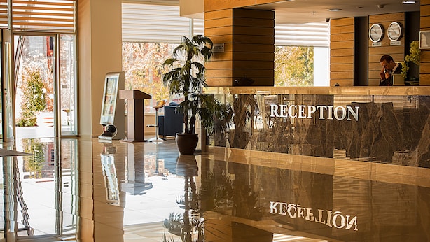 A reception area with a marble counter, a potted plant, and a clock on the wall. - Ataol Can Termal Otel & Spa (Çan)