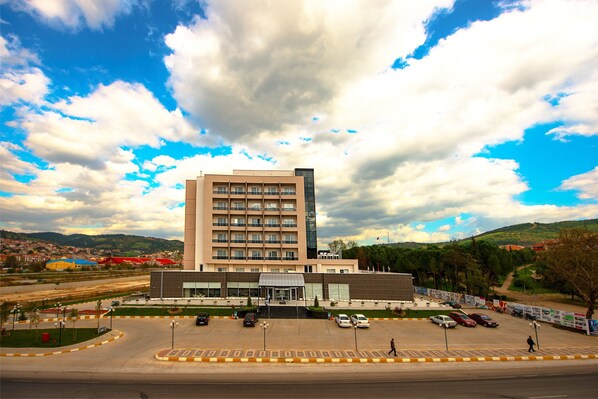A multi-story hotel with a modern facade, a parking lot, and a view of the surrounding landscape. - Ataol Can Termal Otel & Spa (Çan)