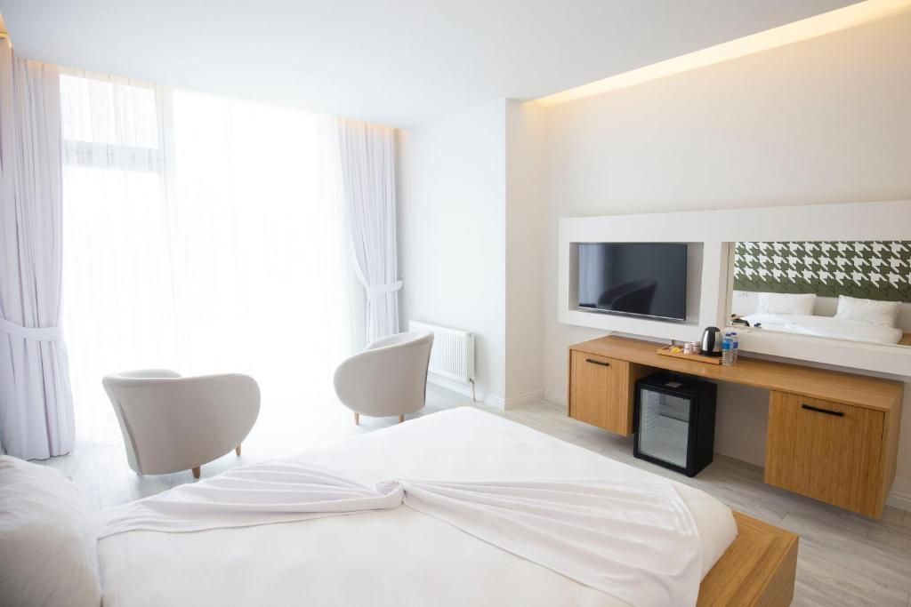 Una habitación de hotel con cama, dos sillas, un escritorio con televisor y un minibar.