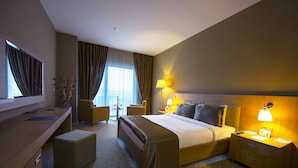 A hotel room with a bed, bedside table, lamp, desk, chair, and a small table with a vase. - Ataol Can Termal Otel & Spa (Çan)