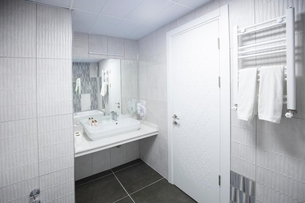 A modern bathroom with a white sink, mirror, and towel rack.