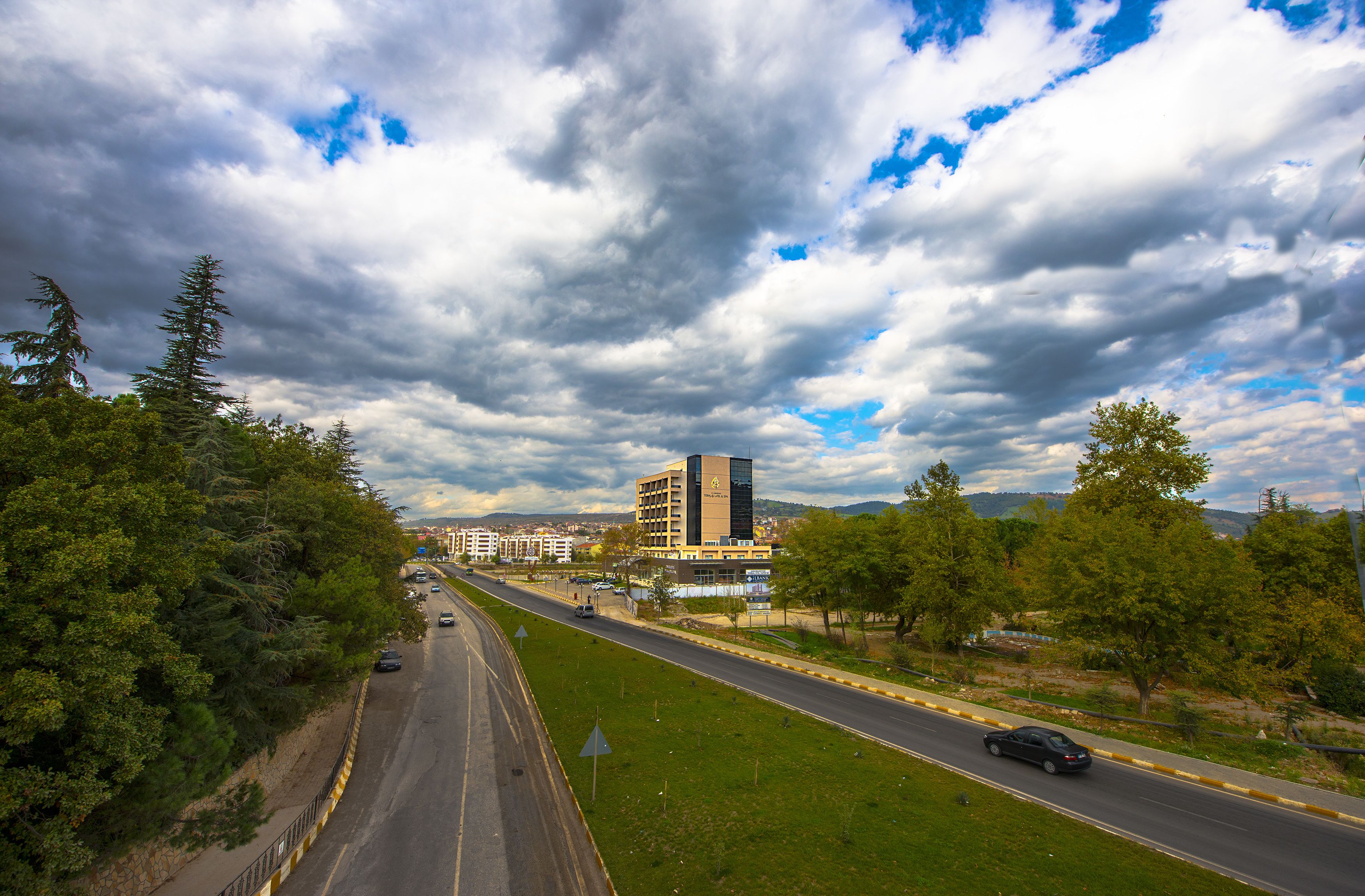 A highway with cars, surrounded by greenery and a building in the distance.
