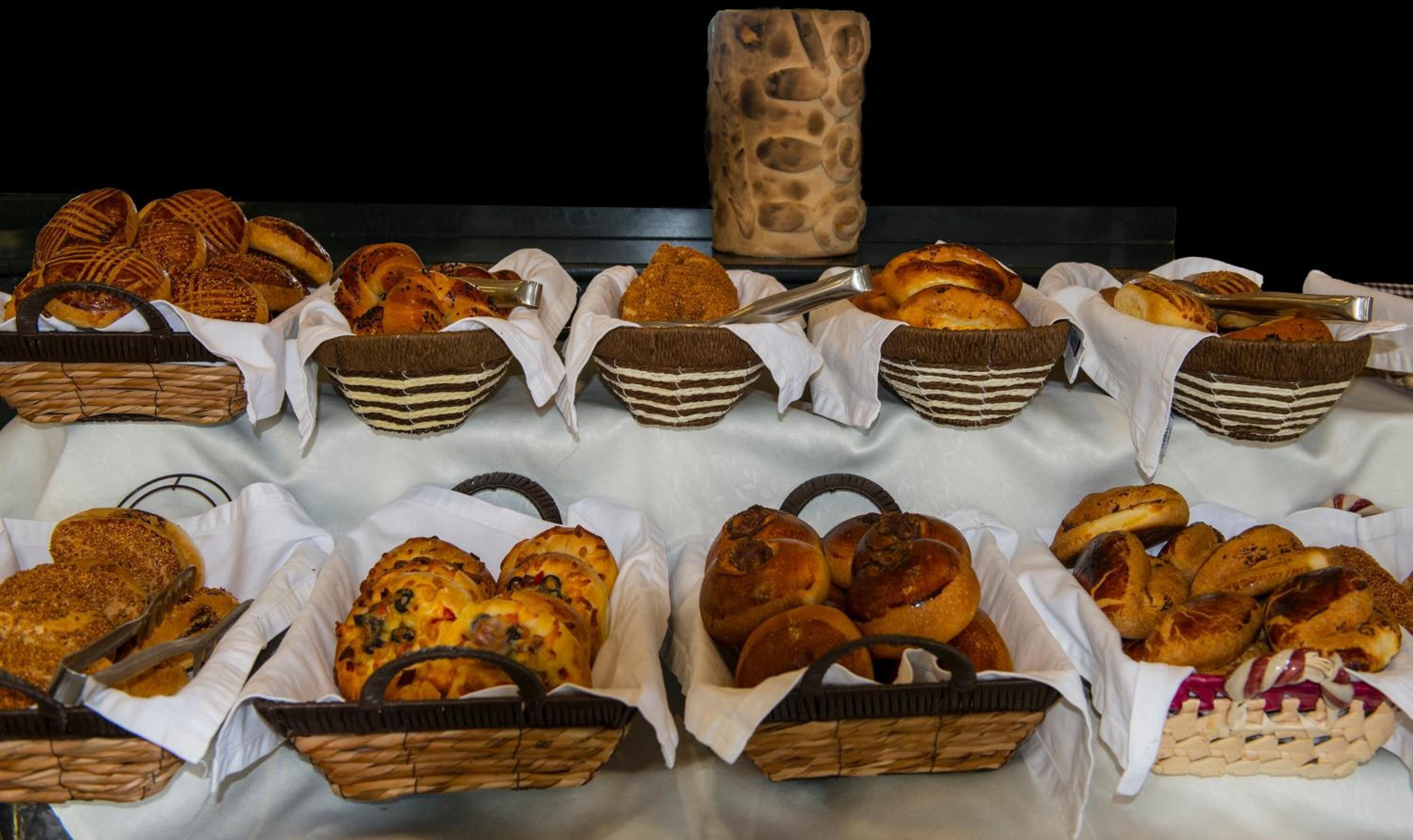 A variety of breads and pastries displayed in baskets on a table.
