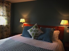 Habitación de hotel con cama, dos lámparas de noche y cortina estampada.