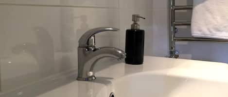 Un baño con un lavabo blanco, grifo cromado y dispensador de jabón.