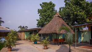 A courtyard with thatched-roof structures, potted plants, and outdoor seating. - Castle City Resort & Suites (Lekki)