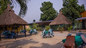 A courtyard with thatched-roof huts, outdoor seating, and potted plants. - Castle City Resort & Suites (Lekki)