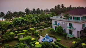 A building with a garden, a fountain, and a view of the ocean.