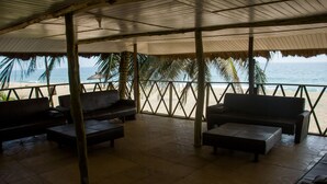 A covered outdoor seating area with a view of the beach and ocean.