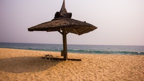 A beach umbrella on a sandy beach with the ocean in the background.
