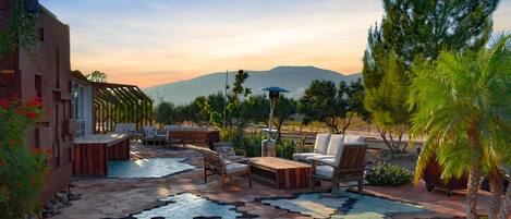 An outdoor patio with hexagonal tiles, wooden furniture, and a view of mountains.