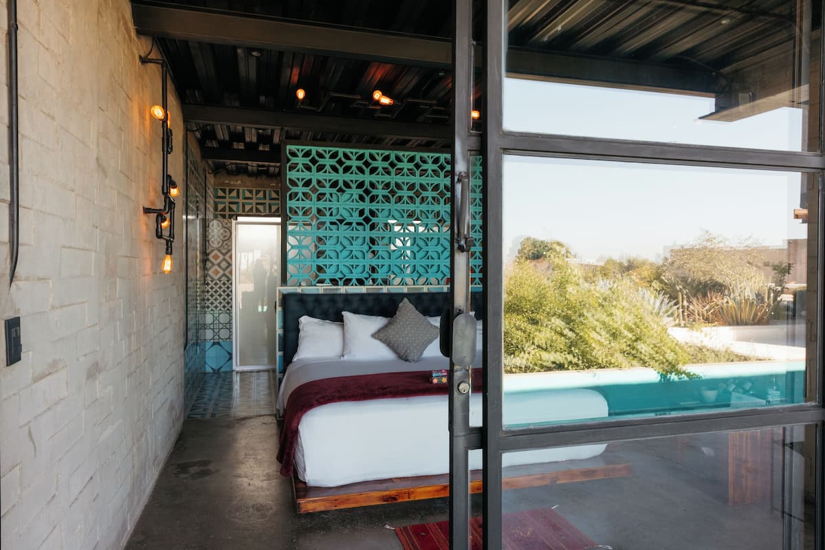 A bedroom with a large bed, a view of a pool, and a patterned wall.
