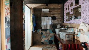 A narrow hallway with patterned tiles, a wooden bench, and a metal sink.