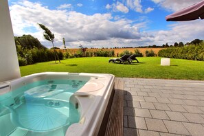 Un bain à remous avec vue sur un champ verdoyant et des arbres en arrière-plan.