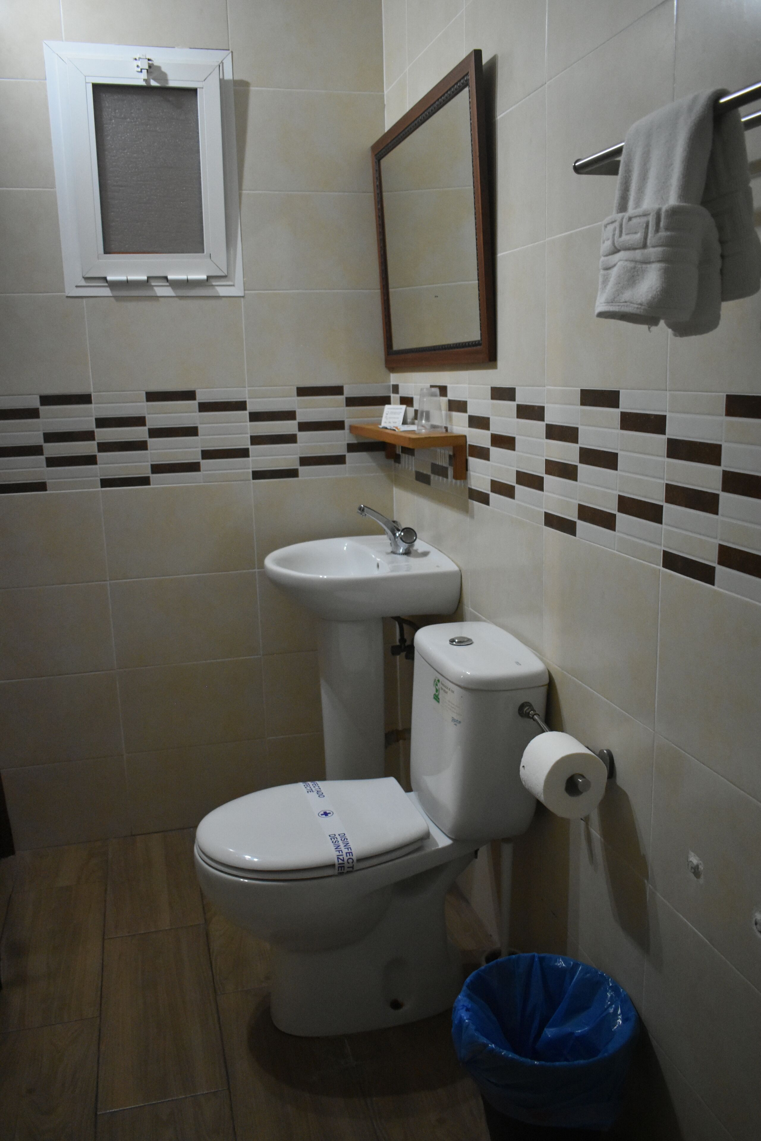 A bathroom with a toilet, sink, and mirror.